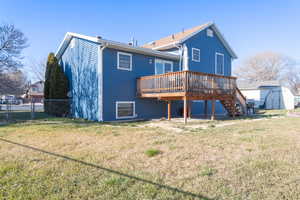 View of east side of the house with newer siding, deck, storage shed, and a large yard.