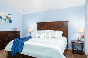 Primary bedroom with vaulted ceiling, ceiling fan, and carpet.