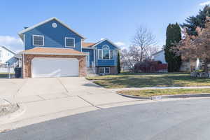 View of front of house with newer siding, concrete driveway, and a 2 car garage with a large yard.