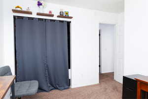 Bedroom used as a home office with carpet floors and baseboards.