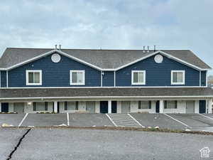 View of front of property featuring uncovered parking and a shingled roof