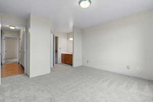 Unfurnished bedroom with light carpet and connected bathroom