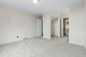 Unfurnished bedroom featuring light colored carpet and a spacious closet
