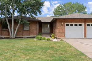 Ranch-style house with a shingled roof, concrete driveway, brick siding, and a front yard
