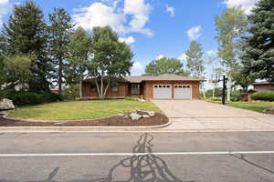 Single story home with a front lawn, concrete driveway, an attached garage, brick siding, and roof with shingles