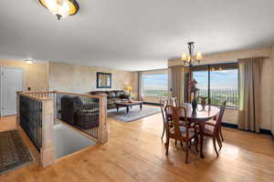 Dining room featuring light wood-style floors, suspended lighting, and a textured wall