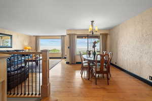 Dining area with a chandelier, light wood-style flooring, and wallpapered walls