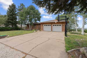 Single story home featuring a front yard, brick siding, an attached garage, and concrete driveway