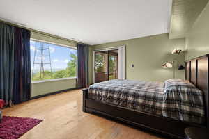 Bedroom featuring hardwood / wood-style flooring, access to outside, and a textured ceiling