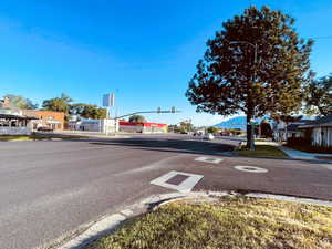 View of asphalt street featuring traffic lights, curbs, sidewalks, and a residential view