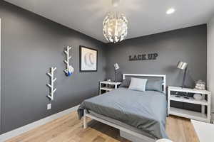 Bedroom with light wood-style flooring, a chandelier, and recessed lighting
