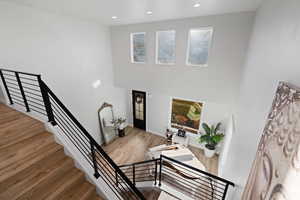 Stairway with recessed lighting, wood finished floors, and a high ceiling
