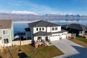 Traditional-style home with a water and mountain view, driveway, stucco siding, and roof with shingles