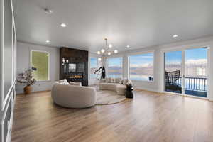 Living room with a chandelier, a large fireplace, light wood-style floors, healthy amount of natural light, and recessed lighting