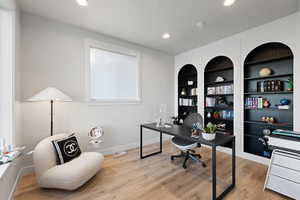 Office with built in shelves, light wood finished floors, and recessed lighting