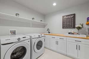 Laundry area featuring independent washer and dryer, cabinet space, recessed lighting, and light marble finish flooring