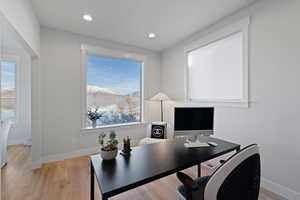 Home office with light wood-style floors and recessed lighting