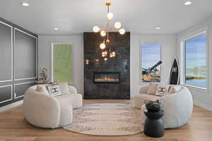 Living area featuring a fireplace, wood finished floors, recessed lighting, a chandelier, and a decorative wall