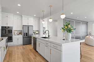 Kitchen featuring white cabinetry, recessed lighting, hanging light fixtures, high end refrigerator, and a center island with sink