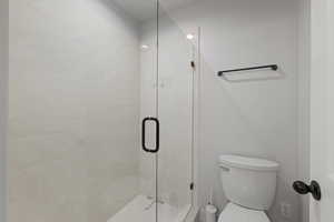 Full bathroom with toilet and a shower stall