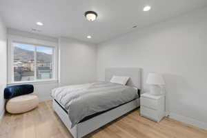 Bedroom with light wood-type flooring, a mountain view, and recessed lighting