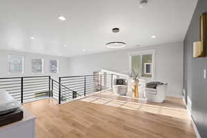 Hall featuring an upstairs landing, light wood-style flooring, and recessed lighting
