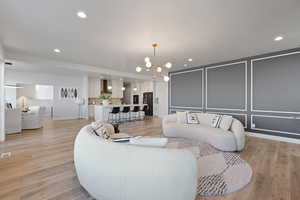 Living area featuring a chandelier, light wood-style floors, a decorative wall, and recessed lighting