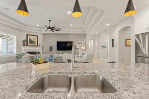 Kitchen featuring light stone countertops, high end refrigerator, hanging light fixtures, a tile fireplace, and recessed lighting