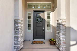 Doorway to property featuring stone siding and stucco siding