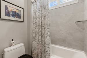 Bathroom featuring toilet and shower / tub combo with curtain