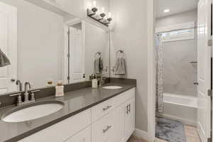 Full bathroom with double vanity, shower / bathtub combination with curtain, and recessed lighting