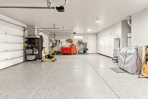 Garage featuring a garage door opener and strapped water heater