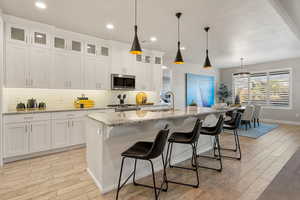 Kitchen featuring light stone counters, a breakfast bar, decorative backsplash, white cabinets, and recessed lighting