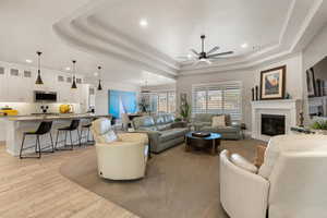 Living area featuring a ceiling fan, light wood finished floors, a fireplace, and recessed lighting