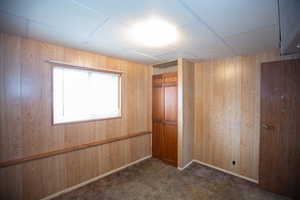 Unfurnished room with dark colored carpet and wooden walls