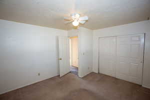 Main bedroom with a textured ceiling, carpet, a closet, and ceiling fan