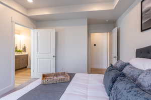 Bedroom with ensuite bath and light wood finished floors