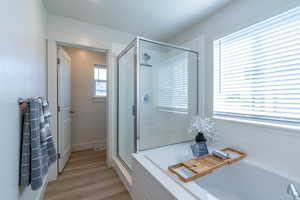 Full bath with a shower stall, a bath, and light wood-style flooring