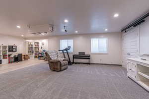 Living area with light colored carpet, a desk, and recessed lighting