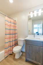 Full bath featuring vanity, light wood finished floors, and shower / bathtub combination with curtain