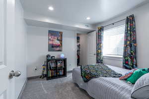 Carpeted bedroom with recessed lighting and a walk in closet