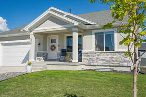 View of front of house featuring a porch, stone siding, and a front yard