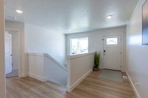 Foyer entrance featuring light wood-style flooring, a textured ceiling, and recessed lighting