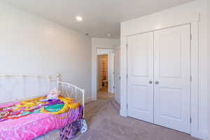 Bedroom with light colored carpet, a closet, and recessed lighting