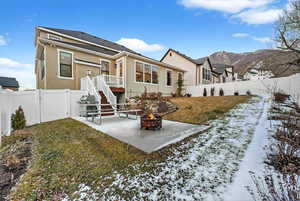 Snow covered back of property with a patio, a fenced backyard, and stucco siding