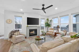 Living area featuring a glass covered fireplace, light wood finished floors, ceiling fan, and recessed lighting