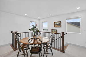 Dining area with light colored carpet, plenty of natural light, and recessed lighting