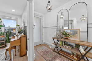 Foyer featuring wainscoting, light wood-type flooring, a decorative wall, and recessed lighting