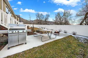 Fenced backyard featuring grilling area, a patio, an outdoor fire pit, and a mountain view