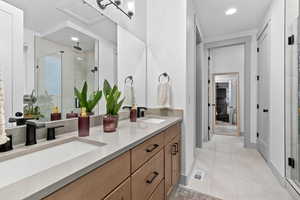 Full bath with a shower stall, double vanity, recessed lighting, and light tile patterned flooring